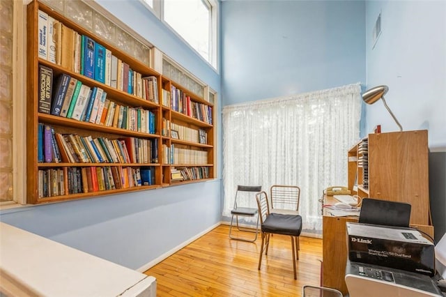 sitting room featuring visible vents, hardwood / wood-style floors, a high ceiling, and baseboards