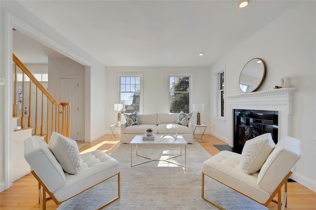 living area featuring recessed lighting, stairway, light wood-style floors, a glass covered fireplace, and baseboards