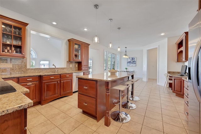 kitchen with stainless steel dishwasher, light tile patterned flooring, a sink, and a breakfast bar