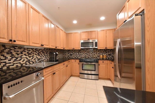 kitchen with dark countertops, tasteful backsplash, light tile patterned floors, stainless steel appliances, and a sink