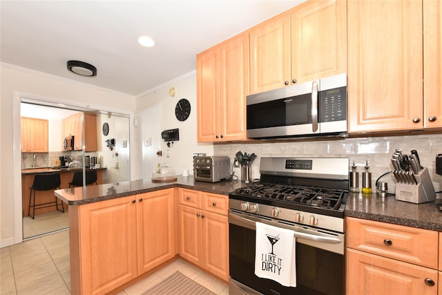 kitchen with a peninsula, appliances with stainless steel finishes, backsplash, light brown cabinetry, and crown molding