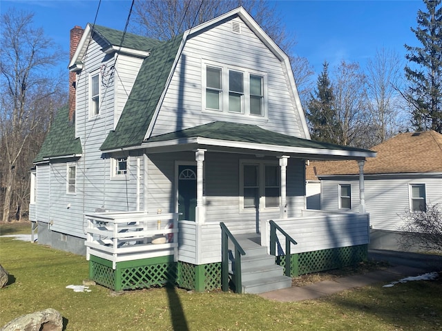 colonial inspired home with a porch, roof with shingles, a front yard, and a gambrel roof