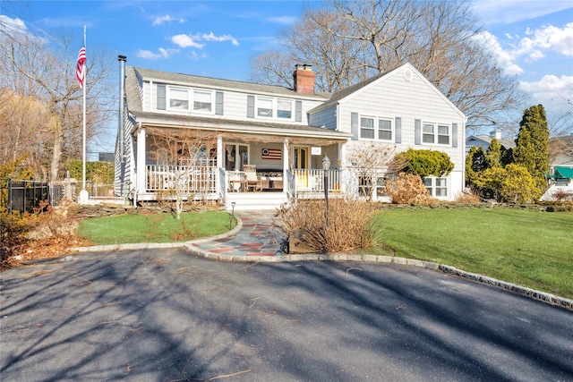 view of front of property with a chimney, fence, a porch, and a front yard