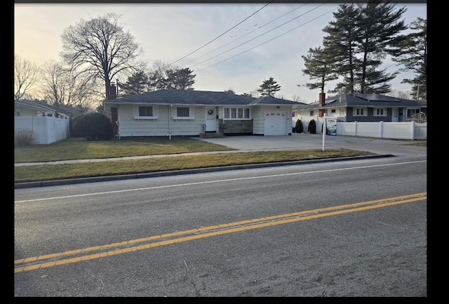 ranch-style home featuring driveway, a chimney, an attached garage, fence, and a front lawn