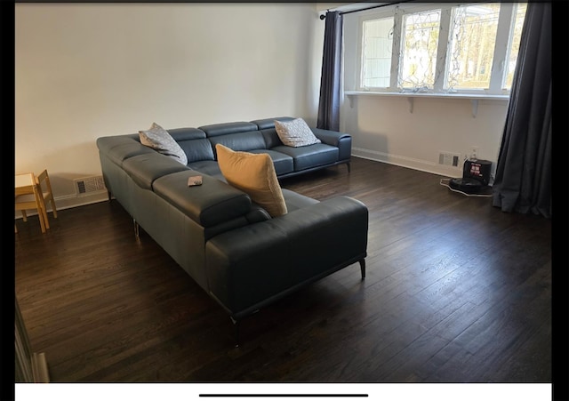 living area with dark wood-style flooring, visible vents, and baseboards