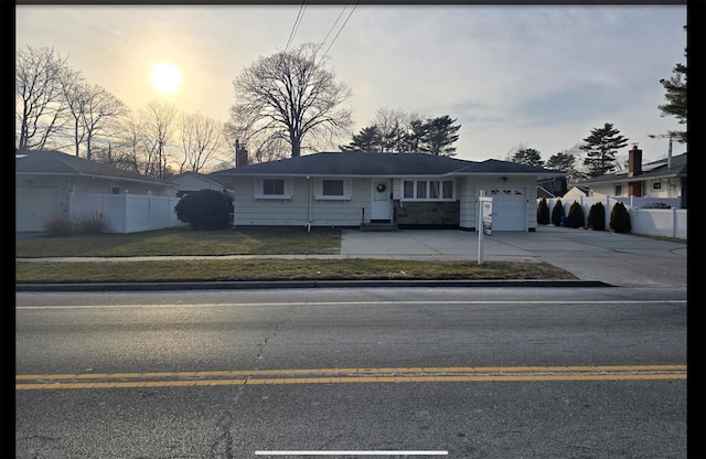 view of front of house featuring a garage, a yard, driveway, and fence