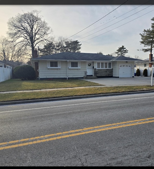 view of front of home with a garage, driveway, fence, and a front yard