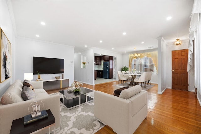 living area with crown molding, a notable chandelier, recessed lighting, light wood-style floors, and baseboards