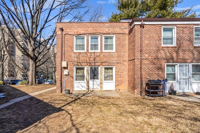 back of property with a yard and brick siding