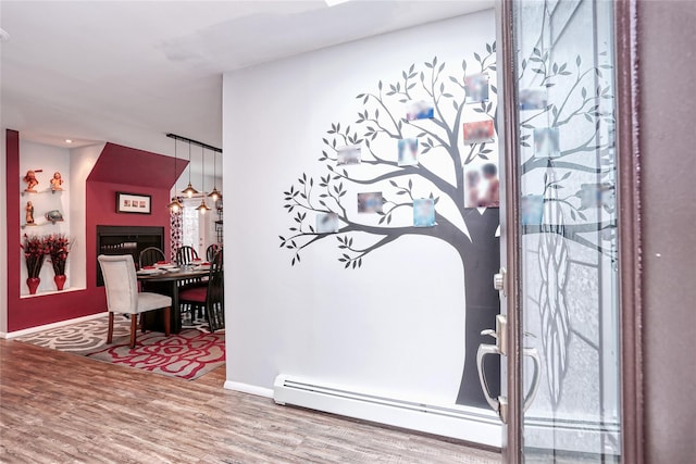 interior space with a baseboard radiator, a fireplace, arched walkways, and wood finished floors