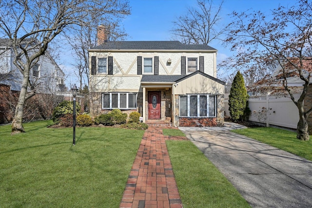 view of front of home with stone siding, a chimney, a front yard, and a shingled roof