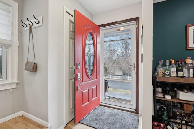 foyer featuring light wood-type flooring, baseboards, and a healthy amount of sunlight