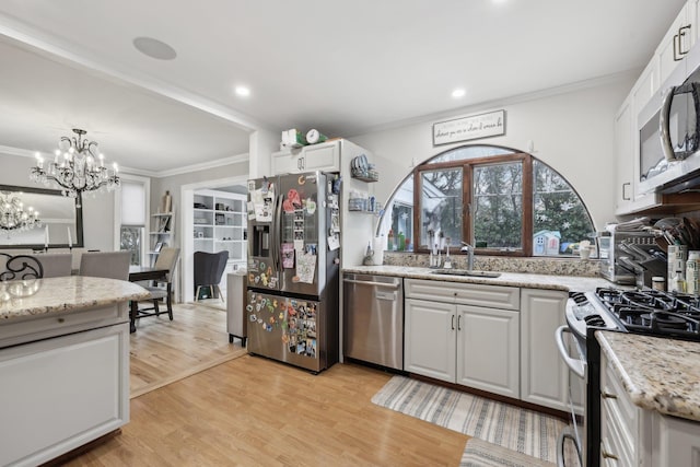 kitchen featuring ornamental molding, stainless steel appliances, light wood-style floors, and a sink