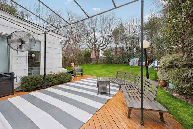 wooden deck featuring an outbuilding, fence, a storage unit, a playground, and a lawn