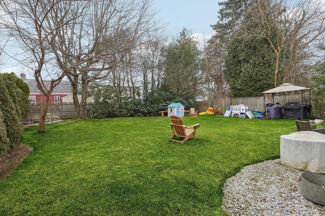 view of yard with a gazebo, an outbuilding, a fenced backyard, and a shed