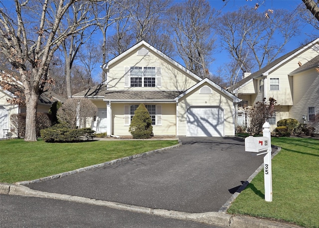 view of front facade with an attached garage, driveway, a front lawn, and a shingled roof