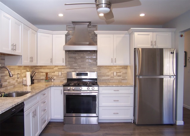 kitchen with appliances with stainless steel finishes, a sink, wall chimney range hood, white cabinetry, and backsplash