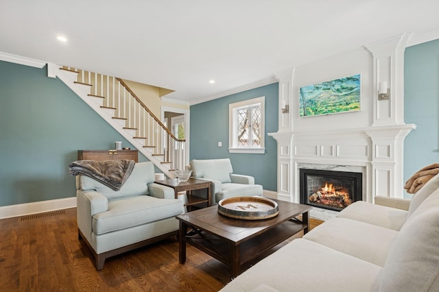 living area featuring a premium fireplace, wood finished floors, baseboards, stairs, and crown molding