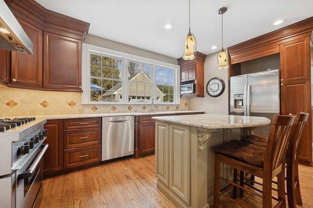 kitchen featuring light stone counters, stainless steel appliances, light wood-style floors, ventilation hood, and backsplash