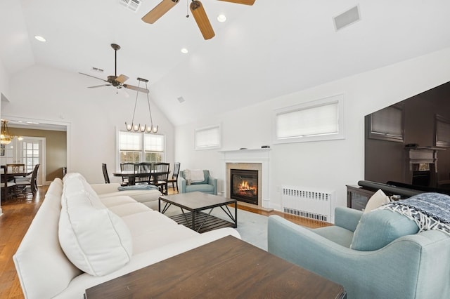 living room featuring visible vents, radiator, a fireplace with flush hearth, wood finished floors, and recessed lighting