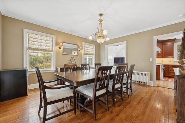 dining room with crown molding, wood-type flooring, an inviting chandelier, and radiator