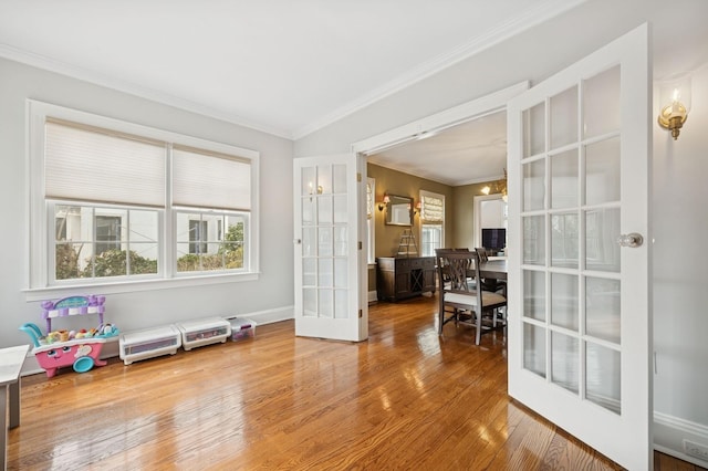 interior space featuring baseboards, wood-type flooring, ornamental molding, french doors, and a chandelier