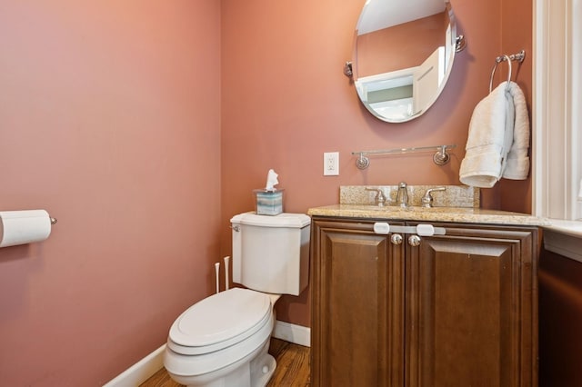 bathroom with toilet, baseboards, wood finished floors, and vanity