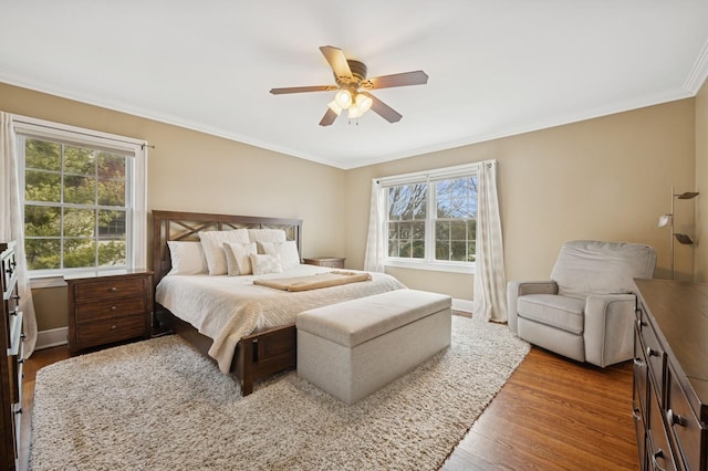 bedroom with crown molding, multiple windows, a ceiling fan, and wood finished floors