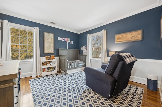 living area featuring baseboards, wood finished floors, visible vents, and crown molding