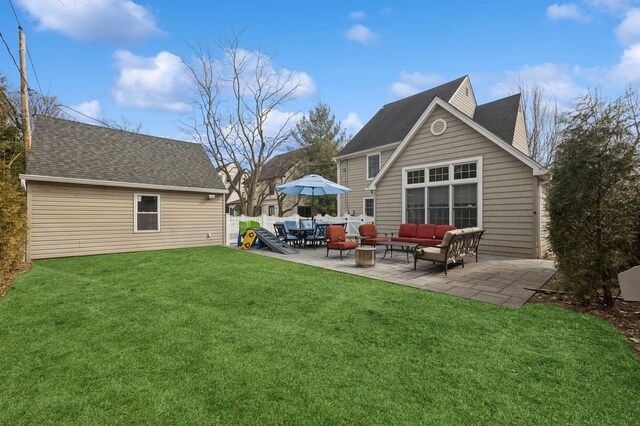 rear view of property featuring a patio, a shingled roof, a lawn, fence, and an outdoor living space