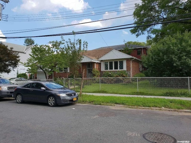 view of front of home with a fenced front yard, a front yard, and brick siding