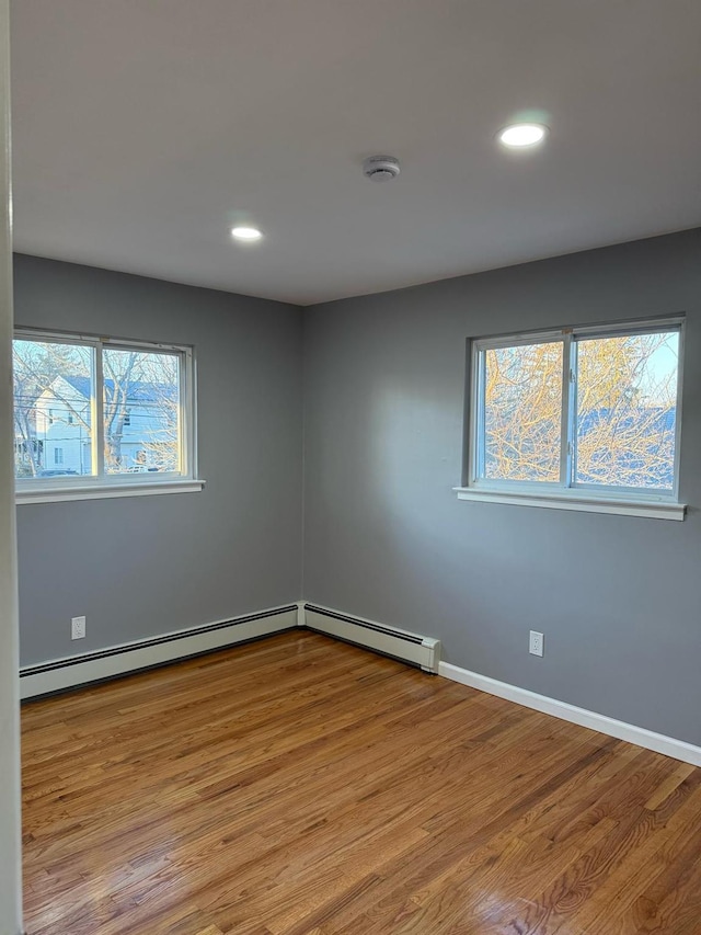 spare room with recessed lighting, baseboards, baseboard heating, and wood finished floors