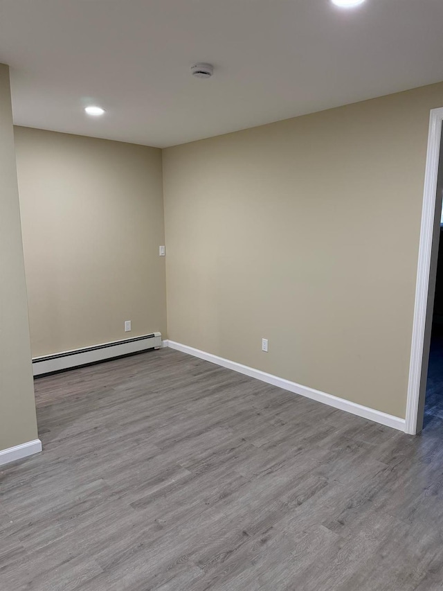 empty room featuring baseboard heating, baseboards, and wood finished floors