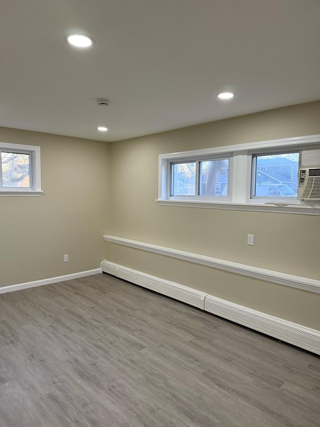 below grade area featuring recessed lighting, wood finished floors, baseboards, and a baseboard radiator