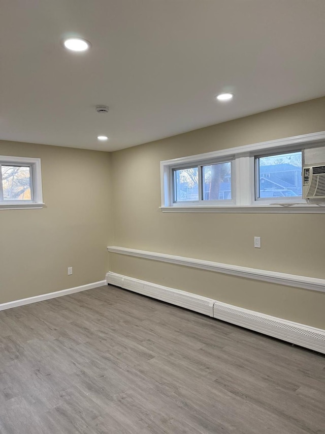 below grade area featuring a baseboard heating unit, recessed lighting, wood finished floors, and baseboards