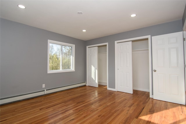 30 Bushwick Ave, Brentwood, NY 11717 - unfurnished bedroom with a baseboard radiator, multiple closets, wood finished floors, recessed lighting, and baseboards