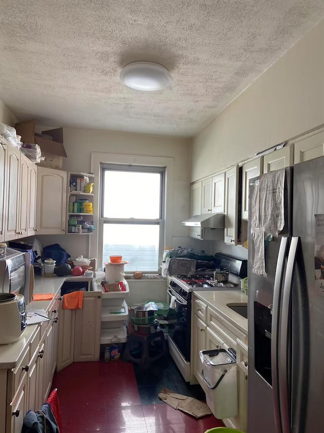 kitchen with range with gas cooktop, stainless steel fridge with ice dispenser, light countertops, a textured ceiling, and under cabinet range hood