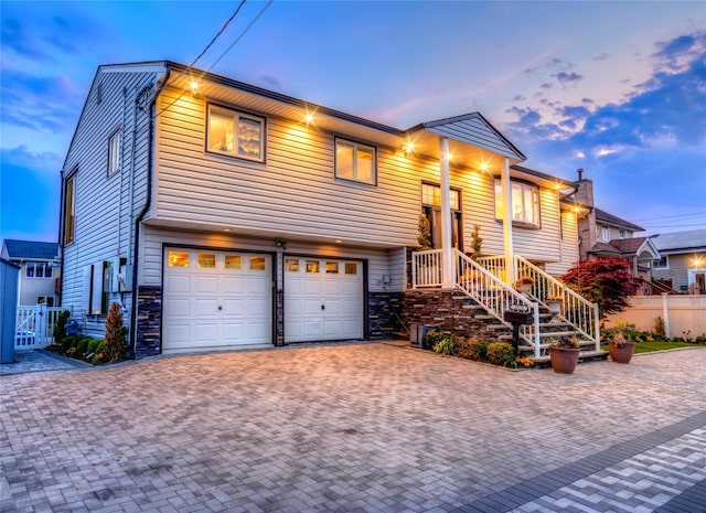 view of front of house featuring a garage, decorative driveway, and fence