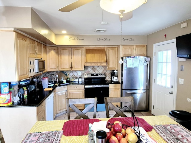 kitchen with light tile patterned floors, custom range hood, decorative backsplash, appliances with stainless steel finishes, and a sink