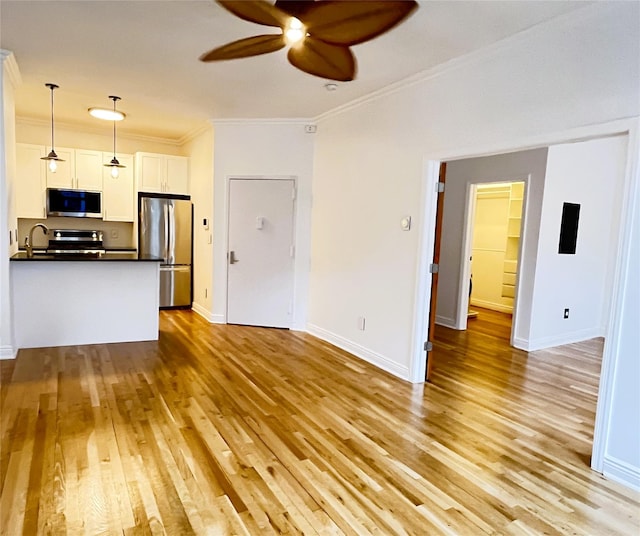 kitchen featuring ornamental molding, appliances with stainless steel finishes, dark countertops, and light wood-style floors