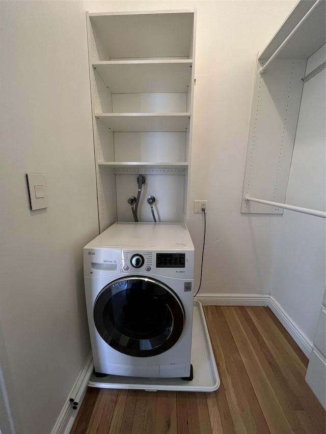 clothes washing area featuring washer / dryer, baseboards, and wood finished floors