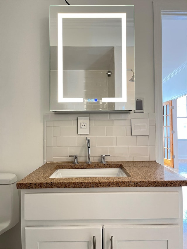 bathroom featuring toilet, decorative backsplash, and vanity