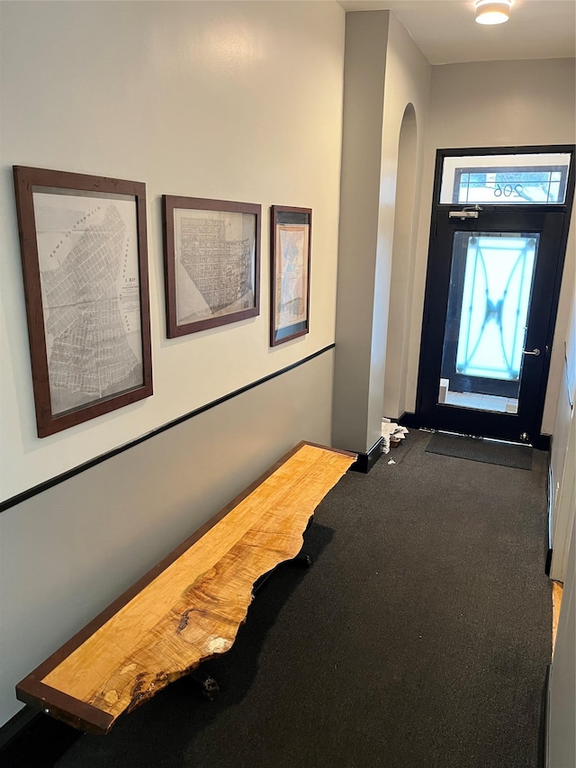 carpeted entrance foyer featuring arched walkways