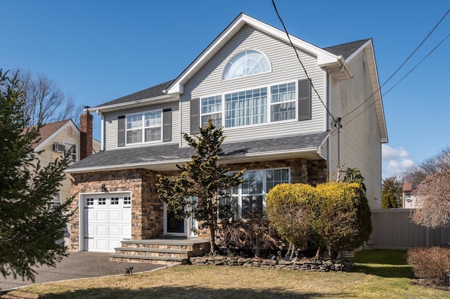 view of front facade featuring fence, a front yard, a garage, stone siding, and driveway