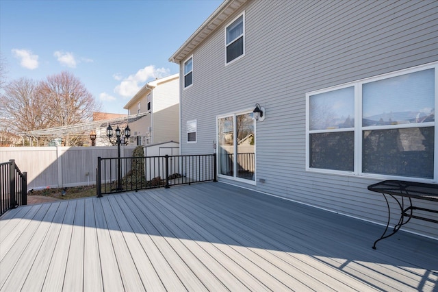 deck featuring a storage shed, an outdoor structure, and fence