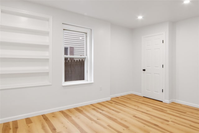 spare room with light wood finished floors, recessed lighting, built in features, and baseboards