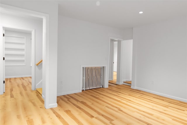 empty room featuring baseboards, recessed lighting, wood finished floors, and radiator