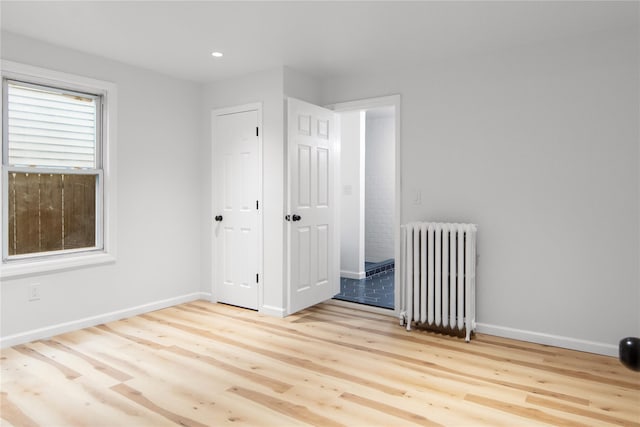 unfurnished room with radiator, baseboards, and wood finished floors