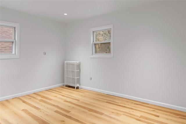 unfurnished room with radiator, baseboards, wood finished floors, and recessed lighting