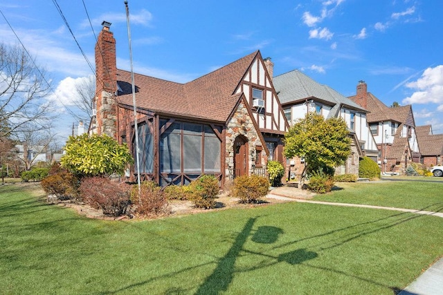 view of front of house with a shingled roof, a front lawn, stone siding, and a chimney